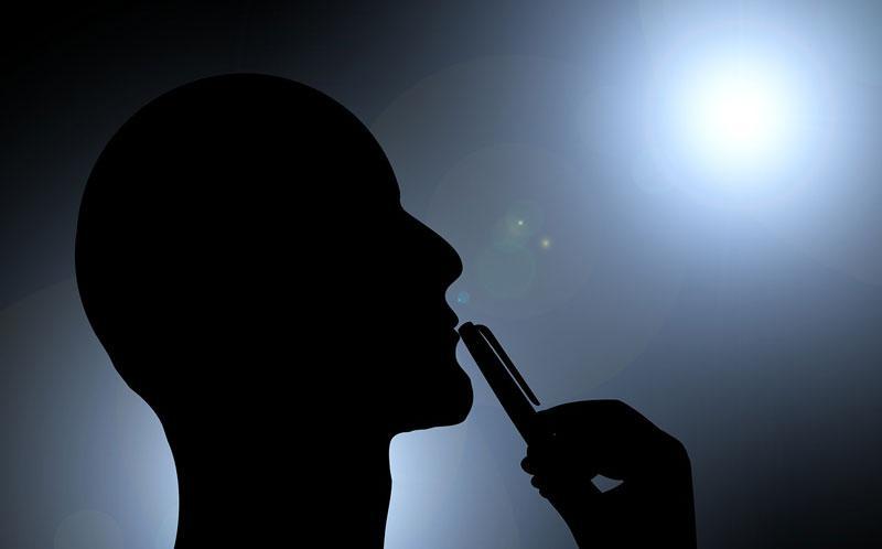 silhouette of man's head with pen touching his lips