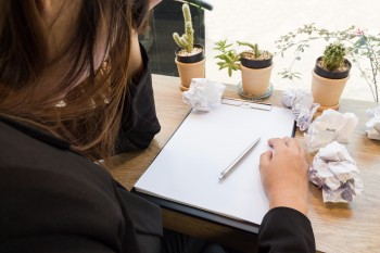 womab starts at a blank page with crumpled pages discarded around her desk