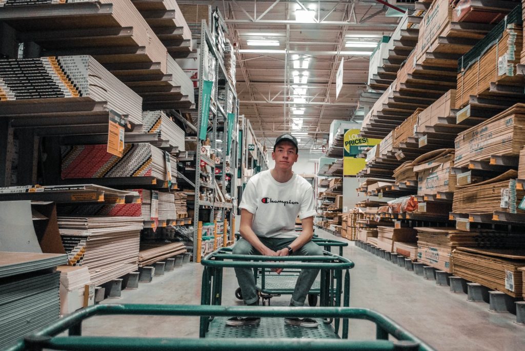 young man sitting on a cart in a lumber warehouse