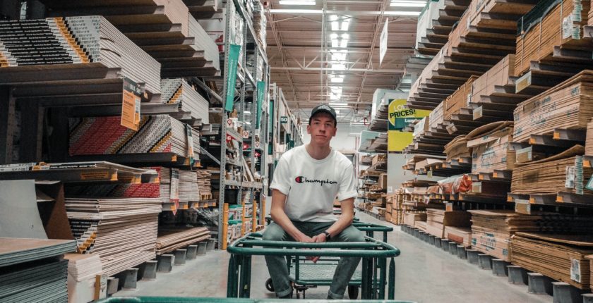 young man sitting on a cart in a lumber warehouse