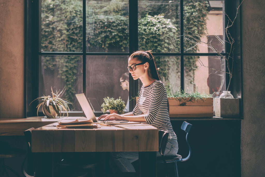 Woman sitting at a cafe table working on laptop