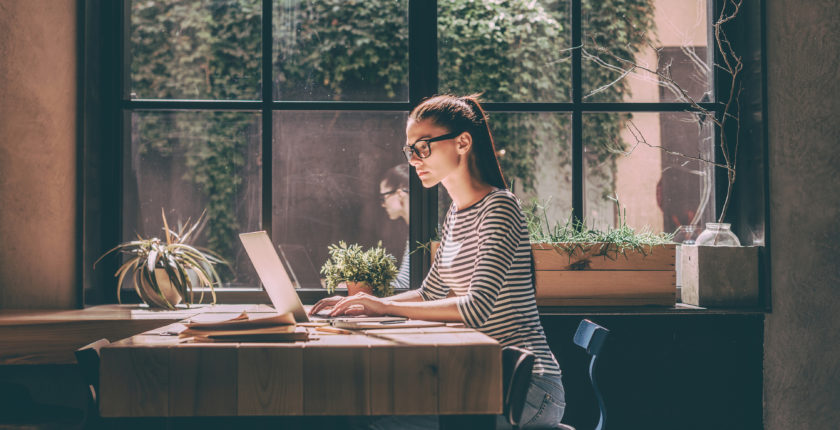 Woman sitting at a cafe table working on laptop