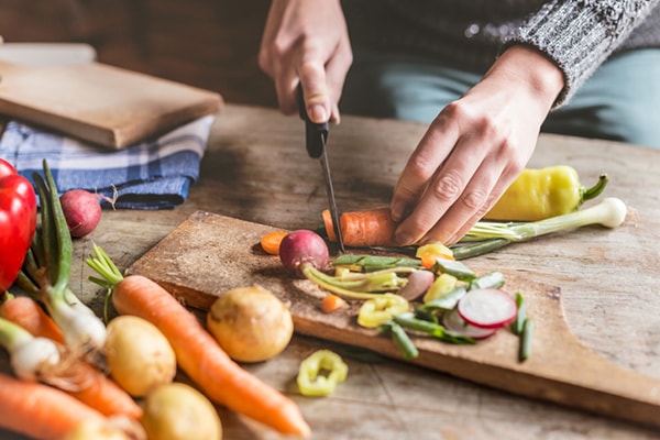 hands chopping carrots and other vegetables