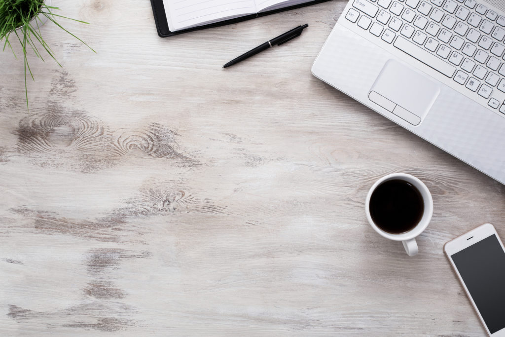 wooden tabletop with laptop, coffee mug, cellphone