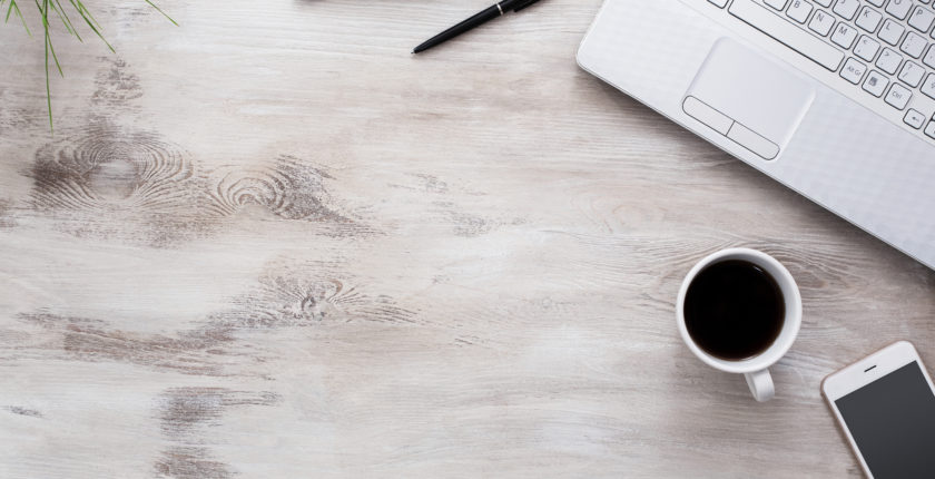 wooden tabletop with laptop, coffee mug, cellphone