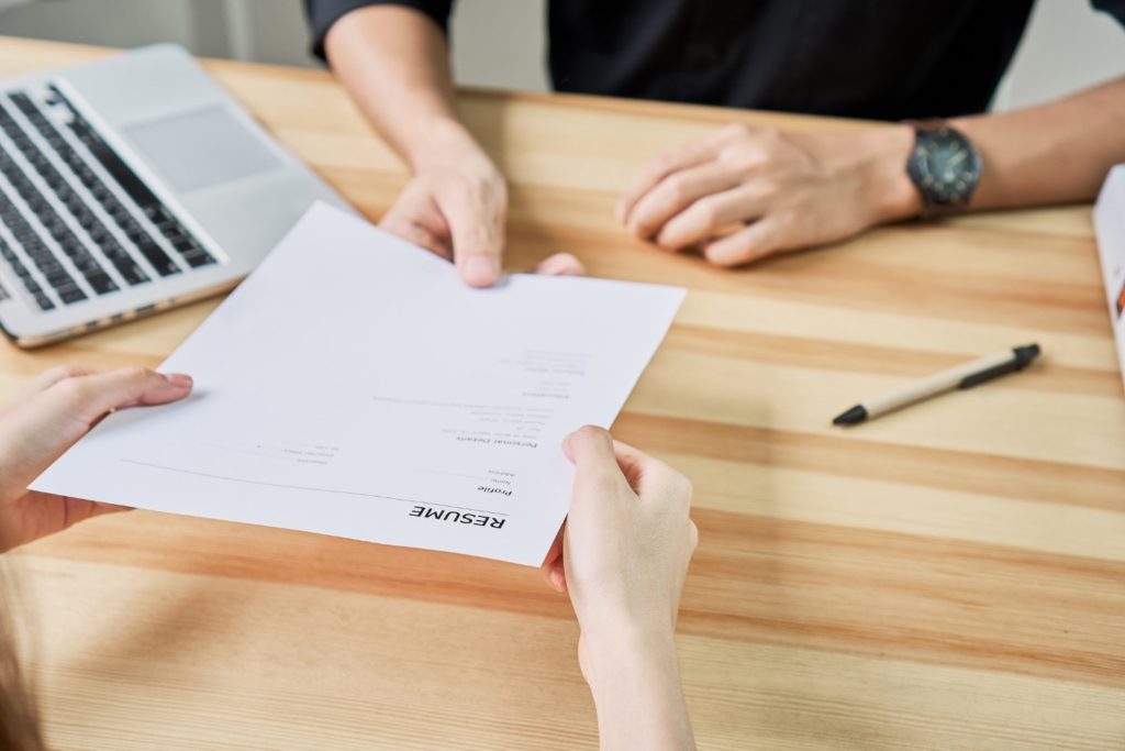 hands passing a resume document