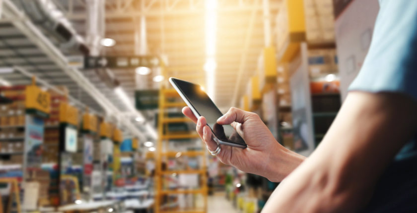 Factory worker using application on mobile smartphone to operate automation for modern trade. Checking order in large warehouse. Import and export the shipping cargo.