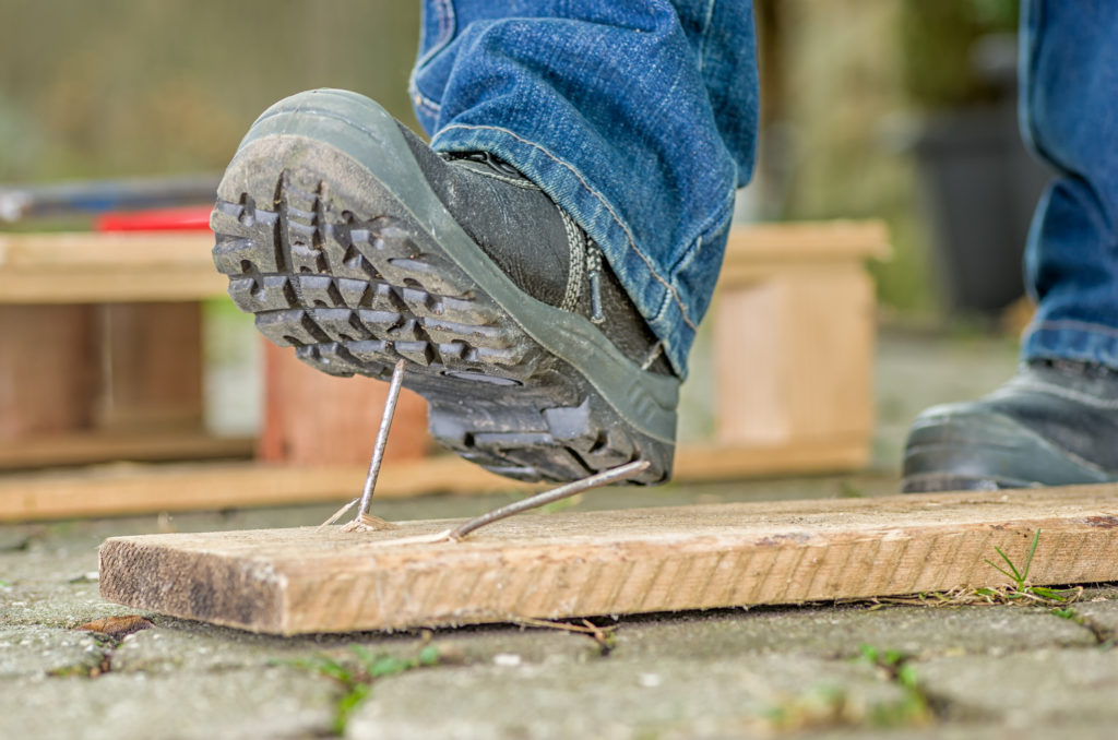 Worker with safety boots steps on a nail