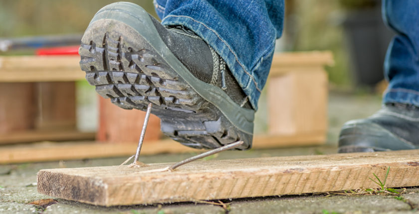 Worker with safety boots steps on a nail