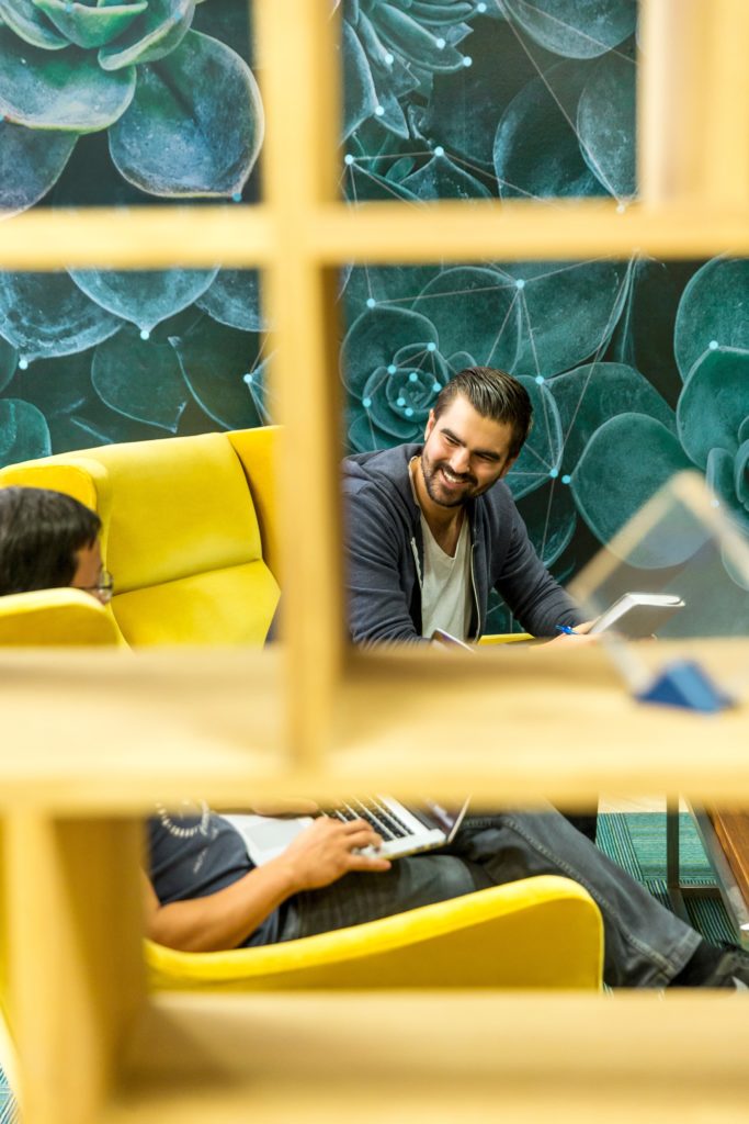 2 men sitting on a coach in a casual workspace