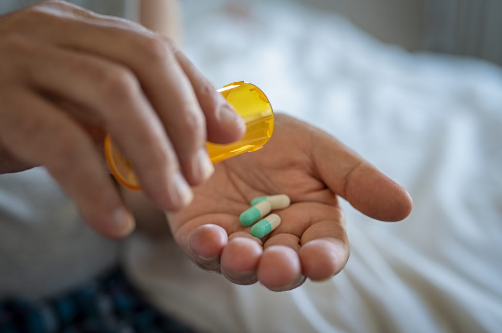 Closeup of man hand pouring capsules from a pill bottle into hand.