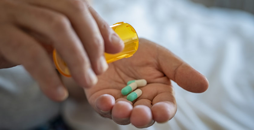 Closeup of man hand pouring capsules from a pill bottle into hand.