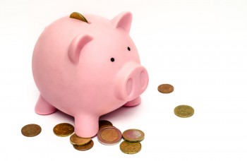 pink ceramic piggy bank with coins on the table around it