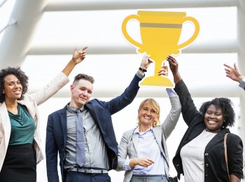 4 people raising a yellow trophy