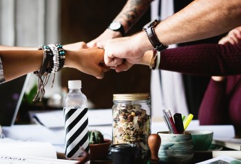 different people's hands connecting in a fist bump