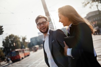 2 people laughing as they walk down the street