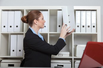 woman placing a document binder onto a shelf