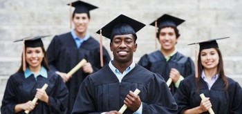 graduating students outside in caps and gowns with diplomas