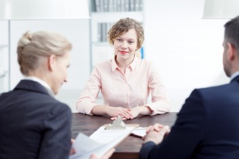 woman being interviewed by two people in suits