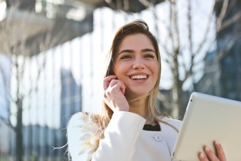 woman smiling while talking on a cellphone outside