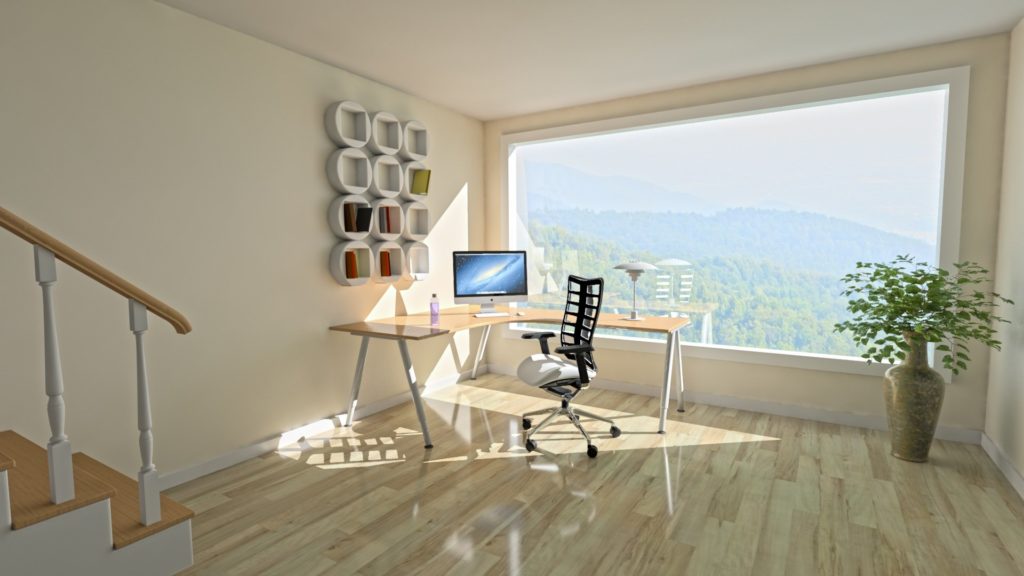 a bright, sunny home office space with a window overlooking forested mountains