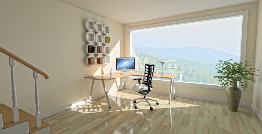 a bright, sunny home office space with a window overlooking forested mountains