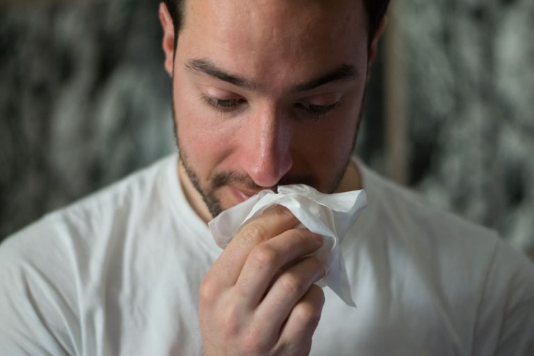 man wiping his nose with a tissue