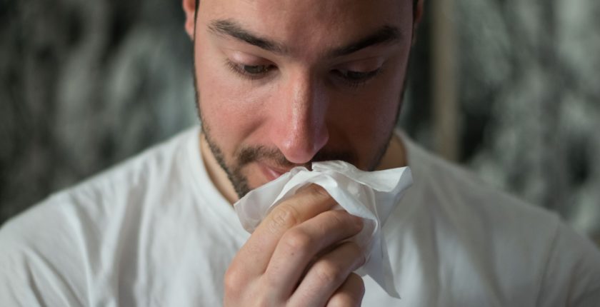 man wiping his nose with a tissue