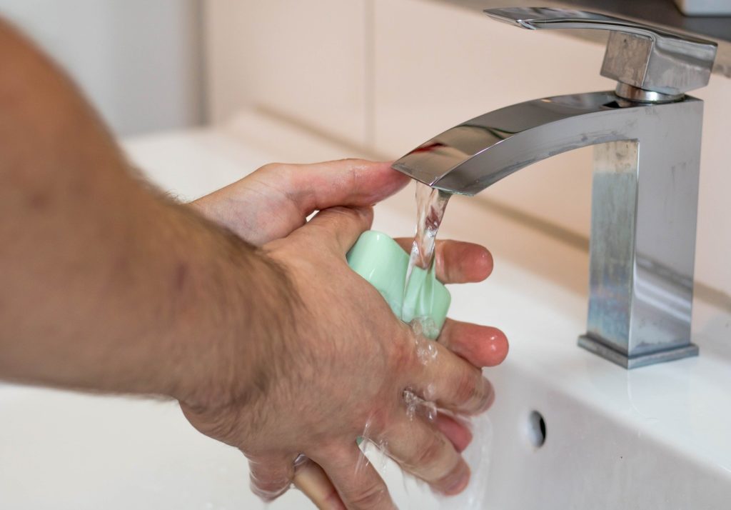 hands being washed under a running tap