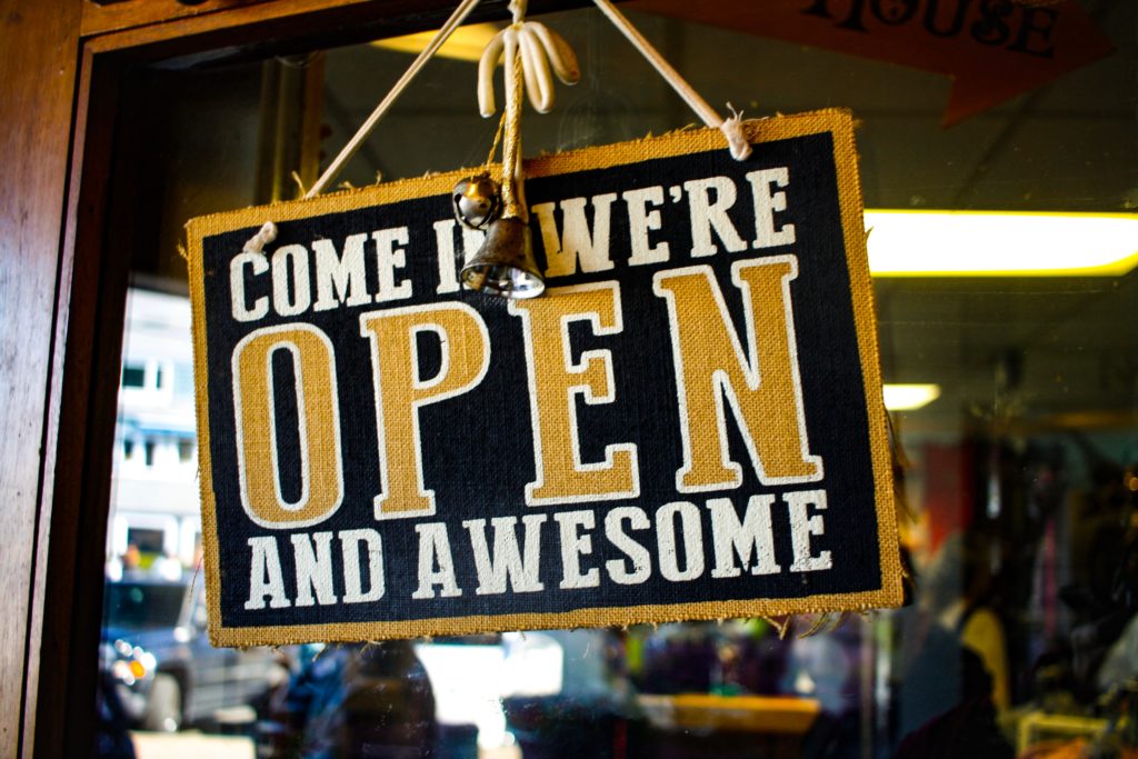 Store window sign that says "Come In We're Open and Awesome"