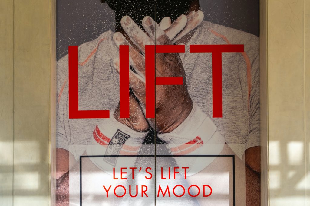 elevator doors with a vinyl stick on it that says "Lift: let's lift your mood"