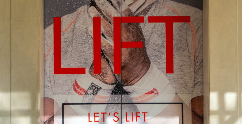 elevator doors with a vinyl stick on it that says "Lift: let's lift your mood"