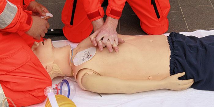 CPR training manquin being worked on by trainees learning to do chest compressions