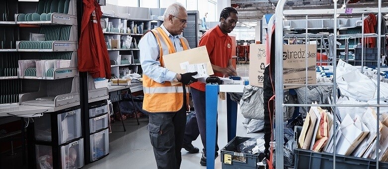 two men in warehouse sorting mail packages