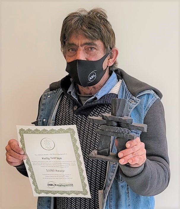 Kelly stands holding certificate and award trophy