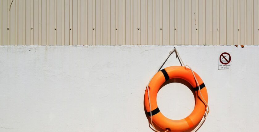 Orange life saver bouy hanging on a wall.