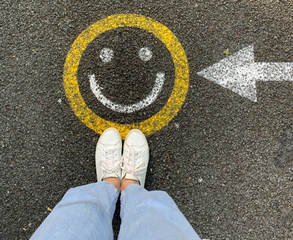 smiley face painted on the road with person standing next to it.