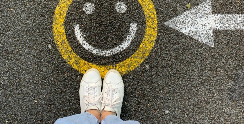 smiley face painted on the road with person standing next to it.