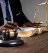 Person sits at a desk with a gavel and a set of scales of justice beside them.