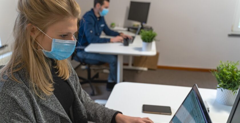 man and woman work at separate desks - returning to the office