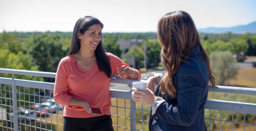 Two ladies chatting outside on a sunny patio having coffee