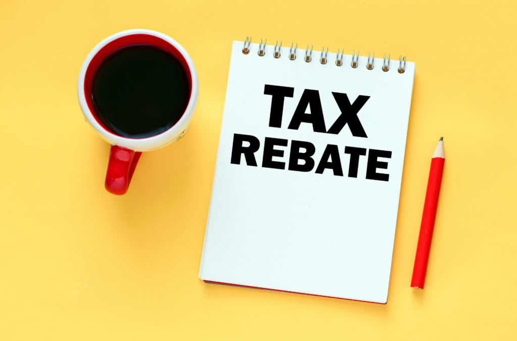 cup of coffee sits beside a pencil and notepad that reads "tax rebate"