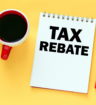 cup of coffee sits beside a pencil and notepad that reads "tax rebate"