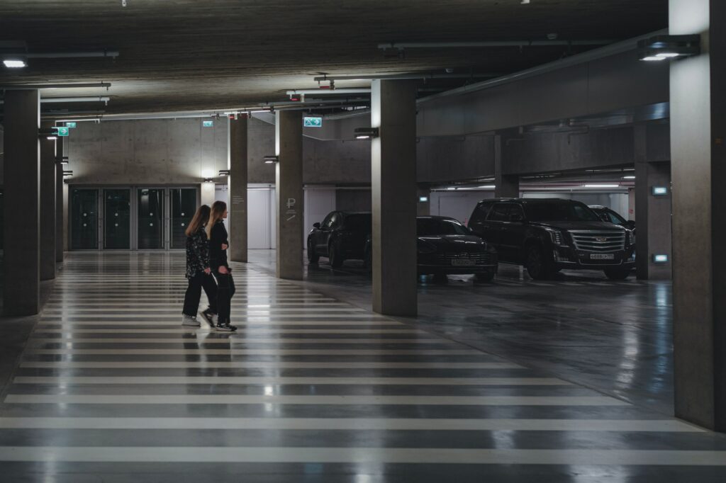 two women walk beside each other in an underground parking lot