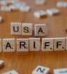 Scrabble tiles on a table spelling out USA TARIFFS