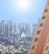 A city under a sunny sky in the background of the image, with a thermometre in the foreground