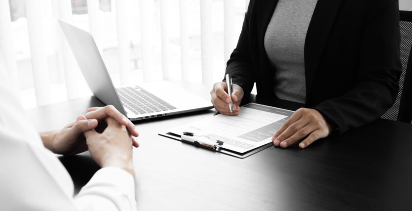 Business professional meeting with a client at a desk, discussing hiring needs and when to use a staffing agency.