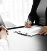 Business professional meeting with a client at a desk, discussing hiring needs and when to use a staffing agency.